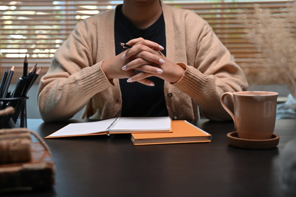 Young woman in warm sweater watching webinar on computer at home.